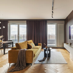 Creative and modern vintage living room interior design with yellow sofa and coffee table on grey carpet. Lamella wall with tv, bookcase and chest of drawers.