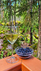 A glass of chilled wine and wild blueberries evoke Finnish Midsummer night, Nordic foraging, and culinary forest magic