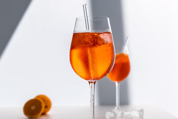 Glas mit leuchtend orangefarbenem Aperol Spritz Cocktail, verziert mit Eiswürfeln, einer frischen Orangenscheibe und einem stilvollen Trinkhalm