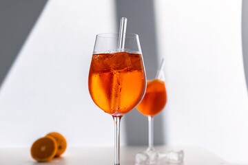 Glas mit leuchtend orangefarbenem Aperol Spritz Cocktail, verziert mit Eiswürfeln, einer frischen Orangenscheibe und einem stilvollen Trinkhalm