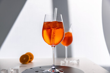 Glas mit leuchtend orangefarbenem Aperol Spritz Cocktail, verziert mit Eiswürfeln, einer frischen Orangenscheibe und einem stilvollen Trinkhalm