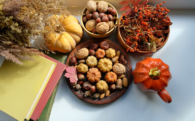 Beautiful autumn background. Pumpkin shape cup, nuts, pumpkin, nature decor, books on table. cozy composition for fall season, Mabon, Halloween, Thanksgiving holiday. symbol of harvest. top view
