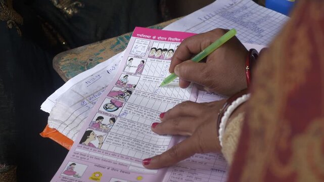 Social healthcare worker filling Mother and Child Protection Card for a pregnant woman by Ministry of Women and Child Development, Begusarai district, Bihar