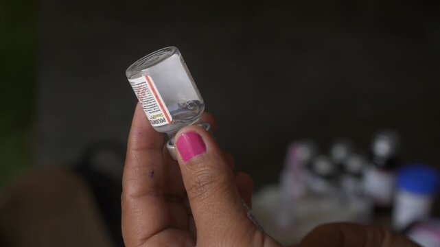 A woman healthcare professional drawing Poliomyelitis poliovirus vaccine into syringe from a vial, National Polio Immunization Drive by Ministry of Women and Family Welfare, Bihar