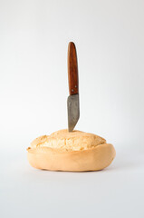 Knife stuck in bread on white background