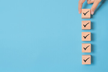 Wood cube with check mark on blue background, Checklist concept, Copy space