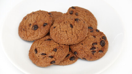 Isolated clipping path of die cut dark chocolate chip cookies on white plate. Closeup tasty bakery organic homemade American biscuit sweet dessert