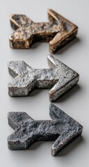 Three stylized arrows, metallic, in shades of gold, silver, and black, arranged vertically on a light gray background