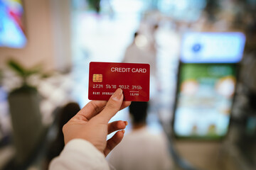 A woman holds a credit card in her hand, symbolizing payment, shopping, finance, banking, consumerism, retail purchases, business, money, and commerce.