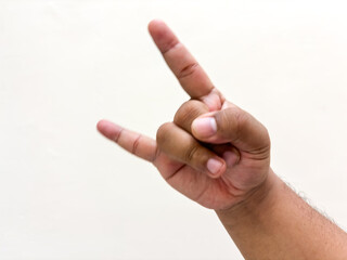 Isolated hand making rock and roll sign against plain backdrop symbolizing rebellious expression...