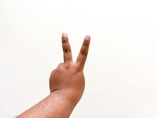 Expressing victory symbol with dark skin tone hand on bright background gesturing positivity and...