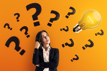 Thoughtful businesswoman surrounded by question marks with glowing lightbulb on orange background...