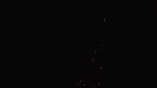 Slow motion of sparks and embers from campfire flying over black background