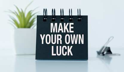 A black notebook with the words Make Your Own Luck written on it
