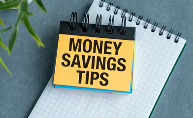 A yellow sticky note with the words Money Saving Tips written on it.