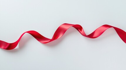 A vibrant red satin ribbon gracefully curves across a stark white background, creating a dramatic contrast. 