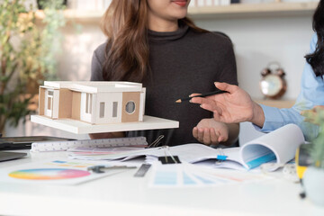 Architectural Model Presentation. Female designers showcasing a miniature house model.