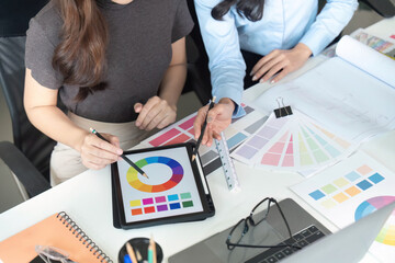 Color Selection. Women architects discussing color schemes and design strategies at a desk.