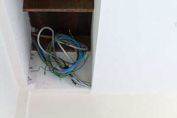 Messy bundle of electrical wiring detail inside ceiling during house renovation. untidy construction site shows complex network and chaos before finishing