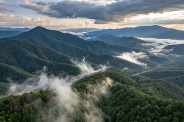 Misty morning sunrise over lush green forested mountain range with dramatic clouds nature landscape