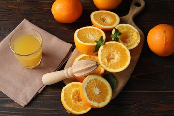 Freshly squeezed orange juice, fruits, mint and juicer on wooden table