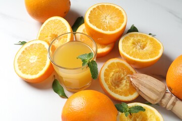 Freshly squeezed orange juice, fruits and juicer on white table, closeup