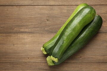 Fresh ripe zucchinis on wooden table, top view. Space for text