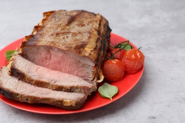 Delicious baked beef meat, tomatoes and basil on grey table, closeup. Space for text
