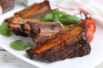Roasted beef ribs, tomatoes and basil on table, closeup