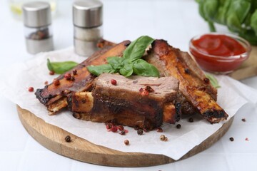 Roasted beef ribs with spices and ketchup on white table, closeup