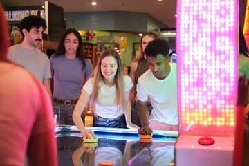 Young friends playing air hockey, enjoying their time together at the arcade center