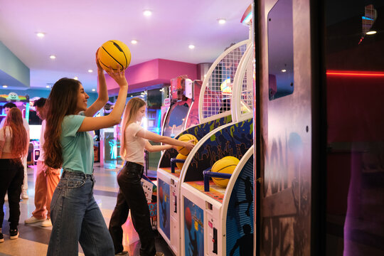 Friends playing arcade basketball game, having fun together in entertainment center