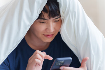 ベッドでスマホを使う男性