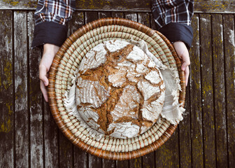 In a wicker basket lined with cloth rests a rustic artisan loaf, its floury crust beautifully...
