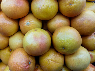 Fresh grapefruits piled together, showcasing vibrant yellow-orange skin texture, perfect for healthy eating, juice, and natural vitamin C source. Ideal for food and nature stock photos