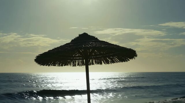 Silhouetted umbrella on beach under warm golden sunset, reflecting calm, romantic and peaceful evening coastal vibes.