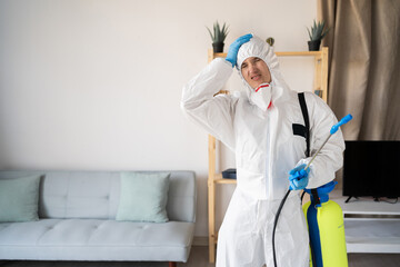 Female exterminator from pest control service working inside house putting hand on head feeling...