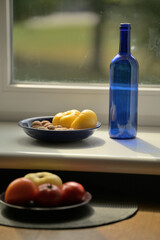 still life with a bottle and vegetables on a sunny windowsill