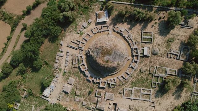Aerial view of the ancient Dharmarajika Stupa ruins, surrounded by lush greenery and the remnants of old structures, Taxila, Punjab, Pakistan.