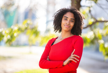 Young woman with curly hair in red sweater smiling outdoors