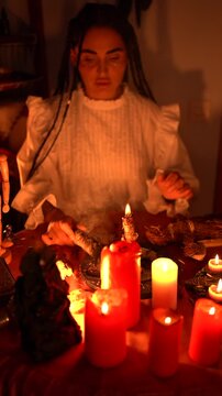 Mystical ritual with burning candles, tarot cards, and a person s hands performing a spiritual ceremony in low light ambiance.