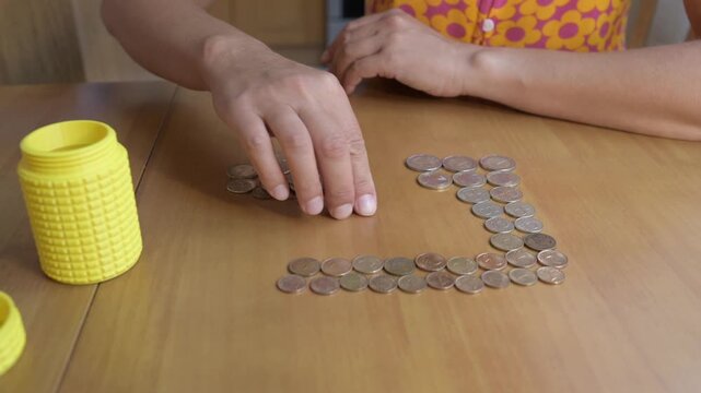 Close-up of hands counting Bulgarian Lev coins on a wooden table. Concept of money, savings, finance, budgeting, economy, investment, banking, and household expenses