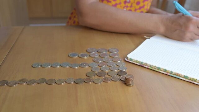 Close-up of hands counting Bulgarian Lev coins on a wooden table. Concept of money, savings, finance, budgeting, economy, investment, banking, and household expenses