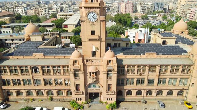 Aerial view of the majestic KMC Building, its clock tower piercing the skyline, solar panels glinting atop, a blend of history and modernity, Karachi, Sindh, Pakistan.