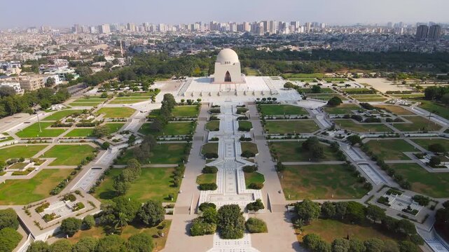 Aerial view of the Mazar-e-Quaid, a white marble mausoleum contrasting with green lawns and pathways, set against a cityscape backdrop, Karachi, Sindh, Pakistan.