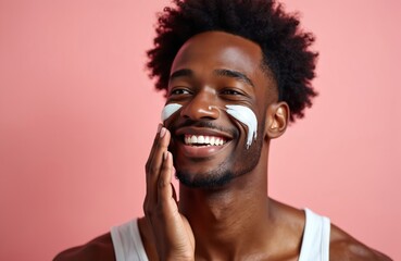 African American man smiles applying facial cream against pink background. Healthy glowing skin achieved through daily skincare routine. Confident, relaxed, attractive male grooming for wellness.