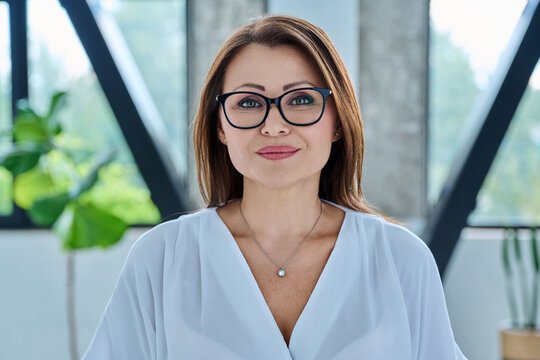 Headshot portrait of middle-aged smiling business woman in office