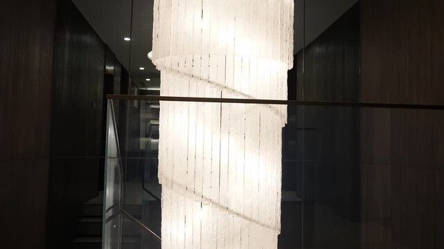 Modern indoor corridor with vertical striped lighting fixtures creating dramatic light and shadow effects