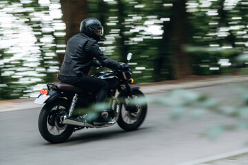 Speed conception, driving. Man in leather clothes on motorcycle is on the road
