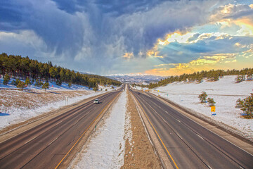 Highway in Rocky Mountains with snow and dramatic sky